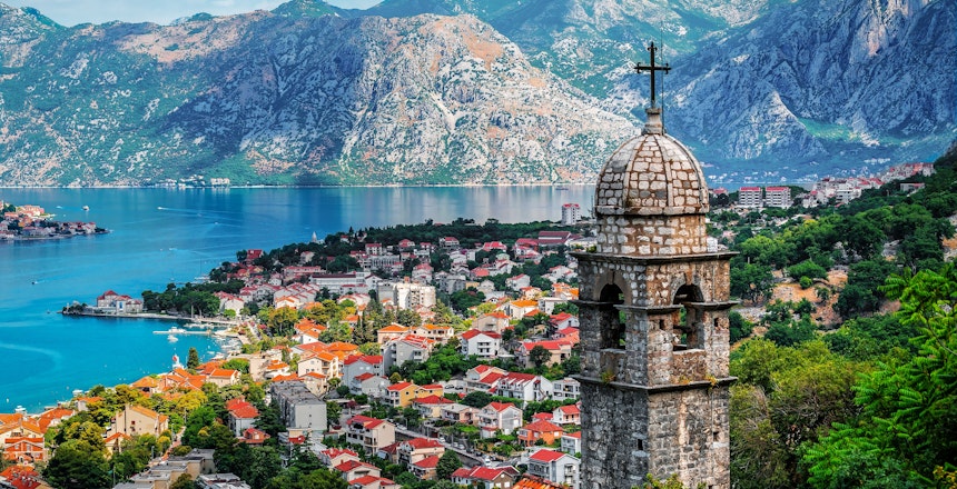 Historisk kirketårn fra Vor Frue af Lindring Kirke med udsigt over Kotors gamle bydel og den smukke bugt omgivet af imponerende bjerge i Montenegro