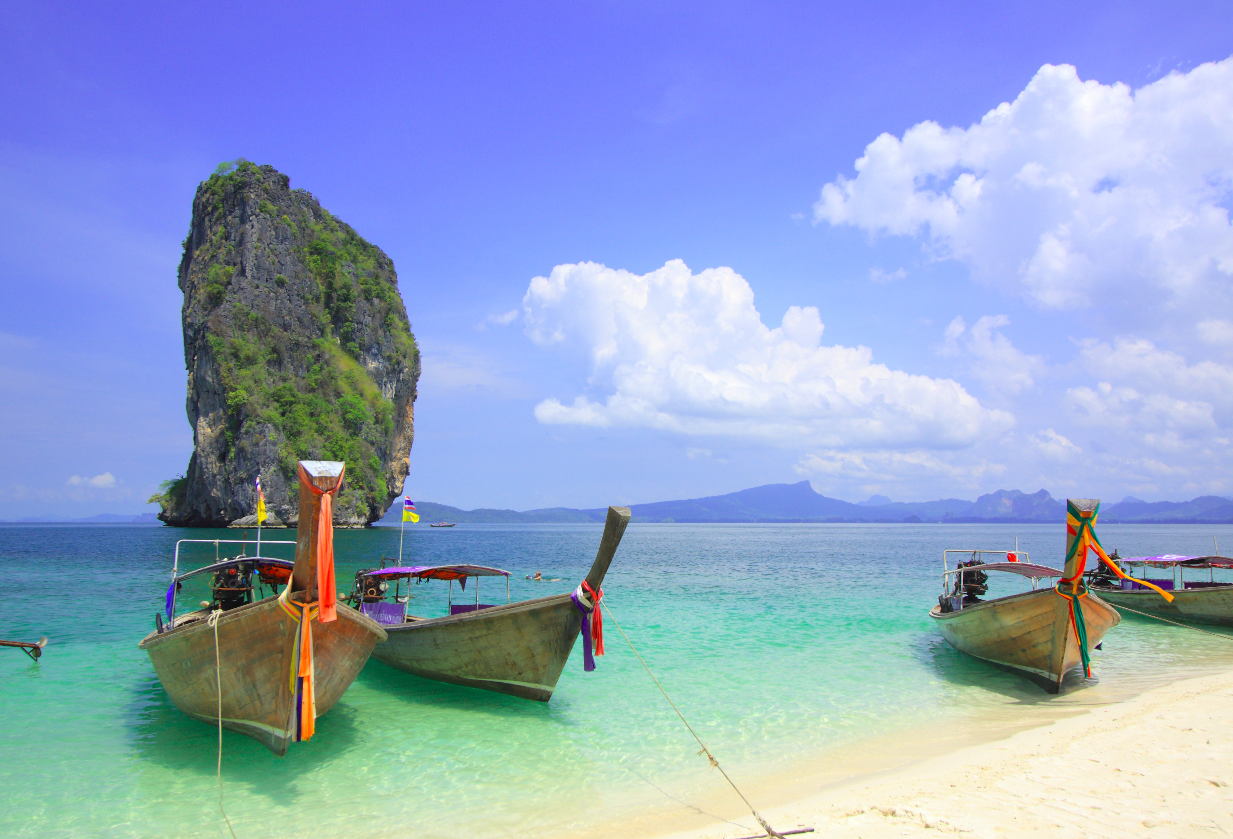 Traditionelle longtail både forankret i krystalklart turkisblåt vand ved Krabi strand Thailand med kalkstensformation