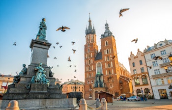 Krakows historiske Markedstorv med Sankt Maria Basilika og Adam Mickiewicz monument ved solnedgang