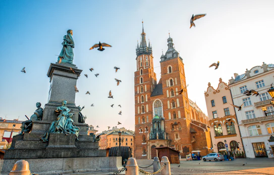 Krakows historiske Markedstorv med Sankt Maria Basilika og Adam Mickiewicz monument ved solnedgang