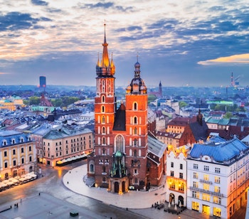Krakows historiske markedsplads Rynek Glowny med den oplyste Mariakirke og middelalderlige bygninger i aftenlys