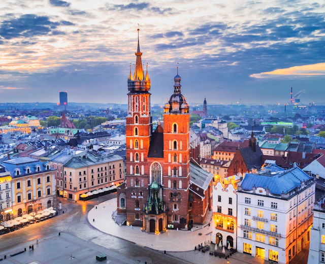 Krakows historiske markedsplads Rynek Glowny med den oplyste Mariakirke og middelalderlige bygninger i aftenlys
