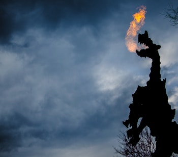 Den berømte Wawel-drage i Krakow der ånder ild mod en dramatisk aftenhimmel - symbolet på byens grundlæggelseslegende om Kong Krak