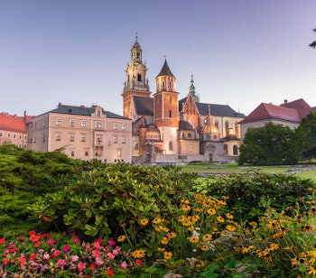 Smuk morgenudsigt over det historiske Wawel-kompleks med den imponerende katedral og det kongelige slot på Wawel-højen, badet i gyldent lys mod en klar blå himmel i Krakow, Polen