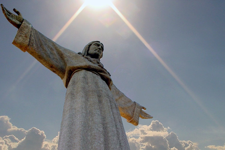 Den majestætiske Kristus-statue i Lissabon badet i gyldent sollys med udsigt over Portugals hovedstad