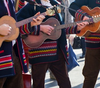 Kroatiske tamburitza-musikere i farverige traditionelle folkedragter spiller ved en kulturfestival i Kroatien