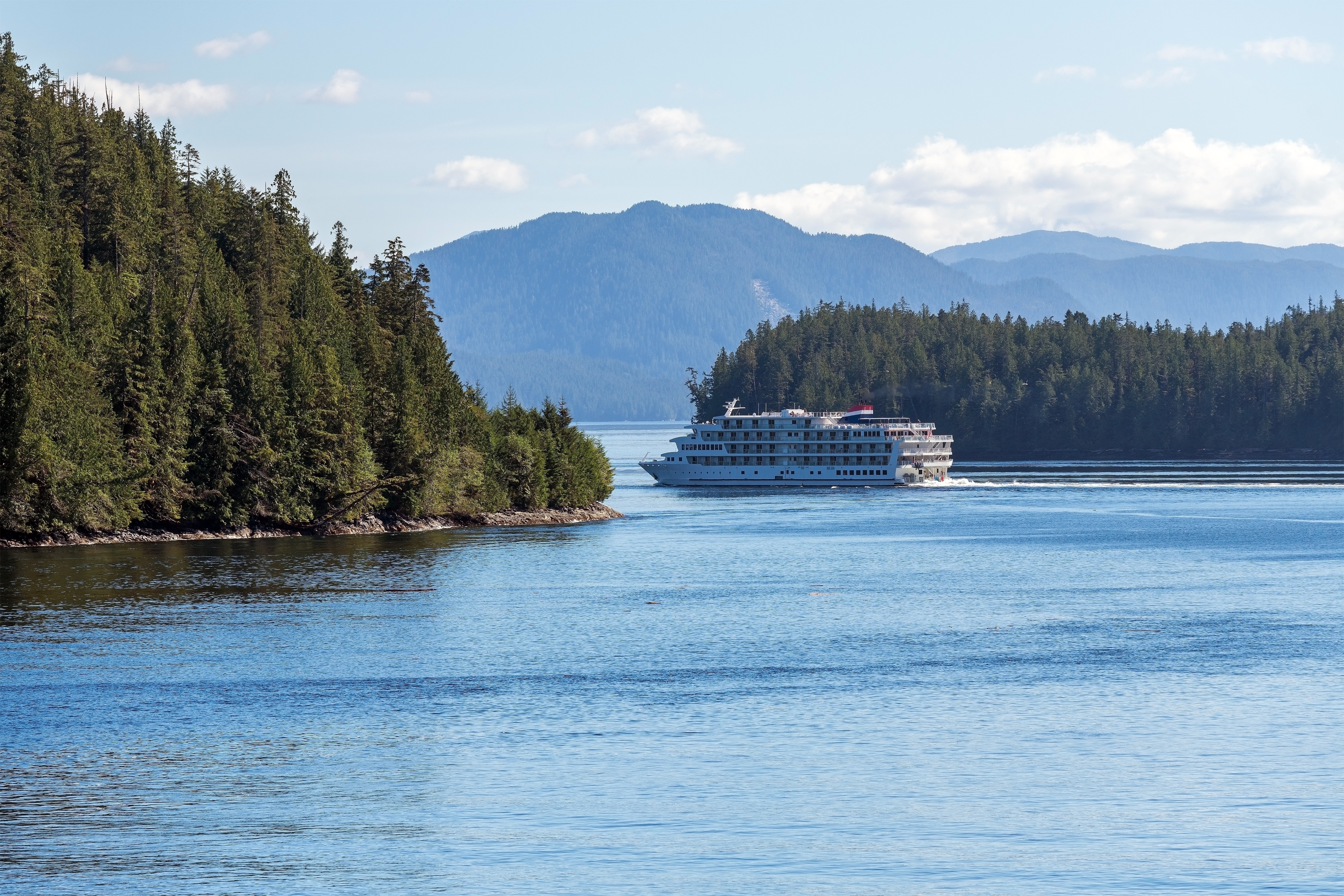 Krydstogtskib sejler gennem den naturskønne Inside Passage mellem Prince Rupert og Port Hardy på Vancouver Island, omgivet af tæt nåleskov og bjerge i British Columbia, Canada
