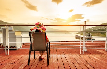 Kvinde med stor hat nyder solopgangen fra dækket på krydstogtsskib på Yangtze-floden i Three Gorges, Kina