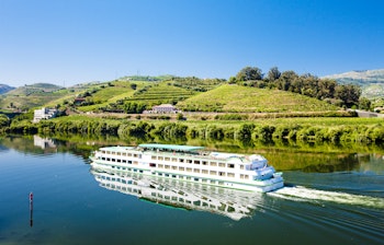 Krydstogtskib sejler på Douro-floden ved Peso da Regua med vinmarker og naturskøn udsigt i Portugal