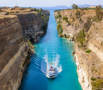 Krydstogtskib sejler gennem den smalle Korinthkanal med høje klippevægge i Grækenland