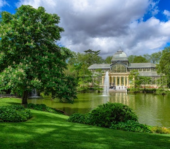 Krystalpaladset i Retiro-parken med spejlbillede i søen, en historisk seværdighed i Madrid, Spanien