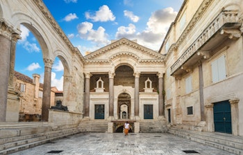 Kvinde går gennem det historiske Peristil-torv i Diokletians Palads i Split, Kroatien i de tidlige morgentimer