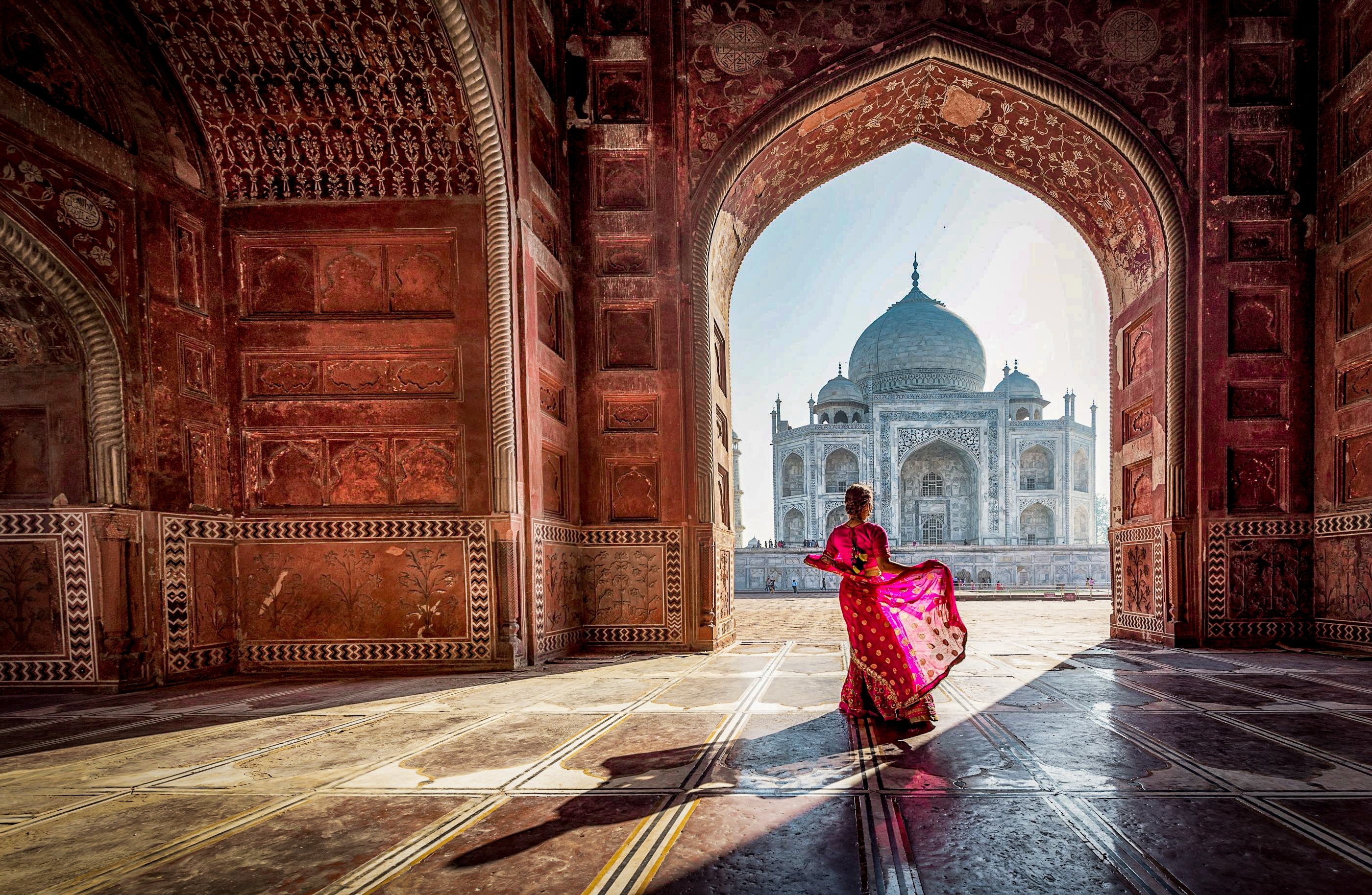 Kvinde i traditionel rød sari ved Taj Mahal moske indgang i Agra Indien