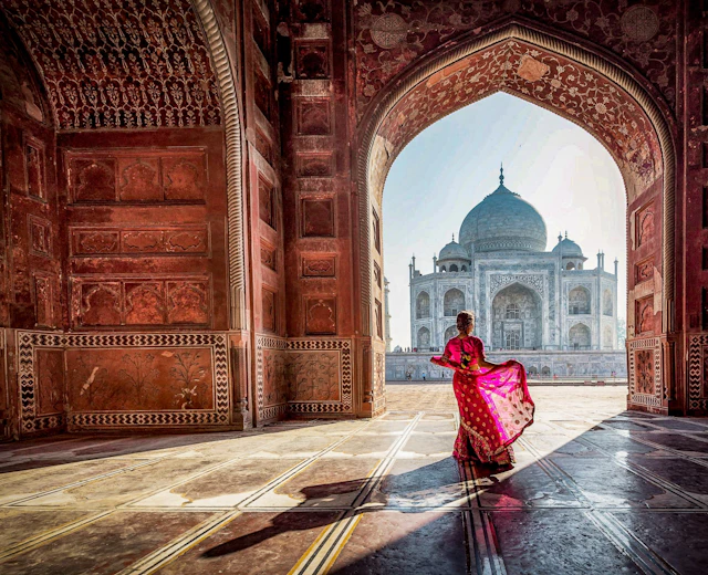 Kvinde i traditionel rød sari ved Taj Mahal moske indgang i Agra Indien