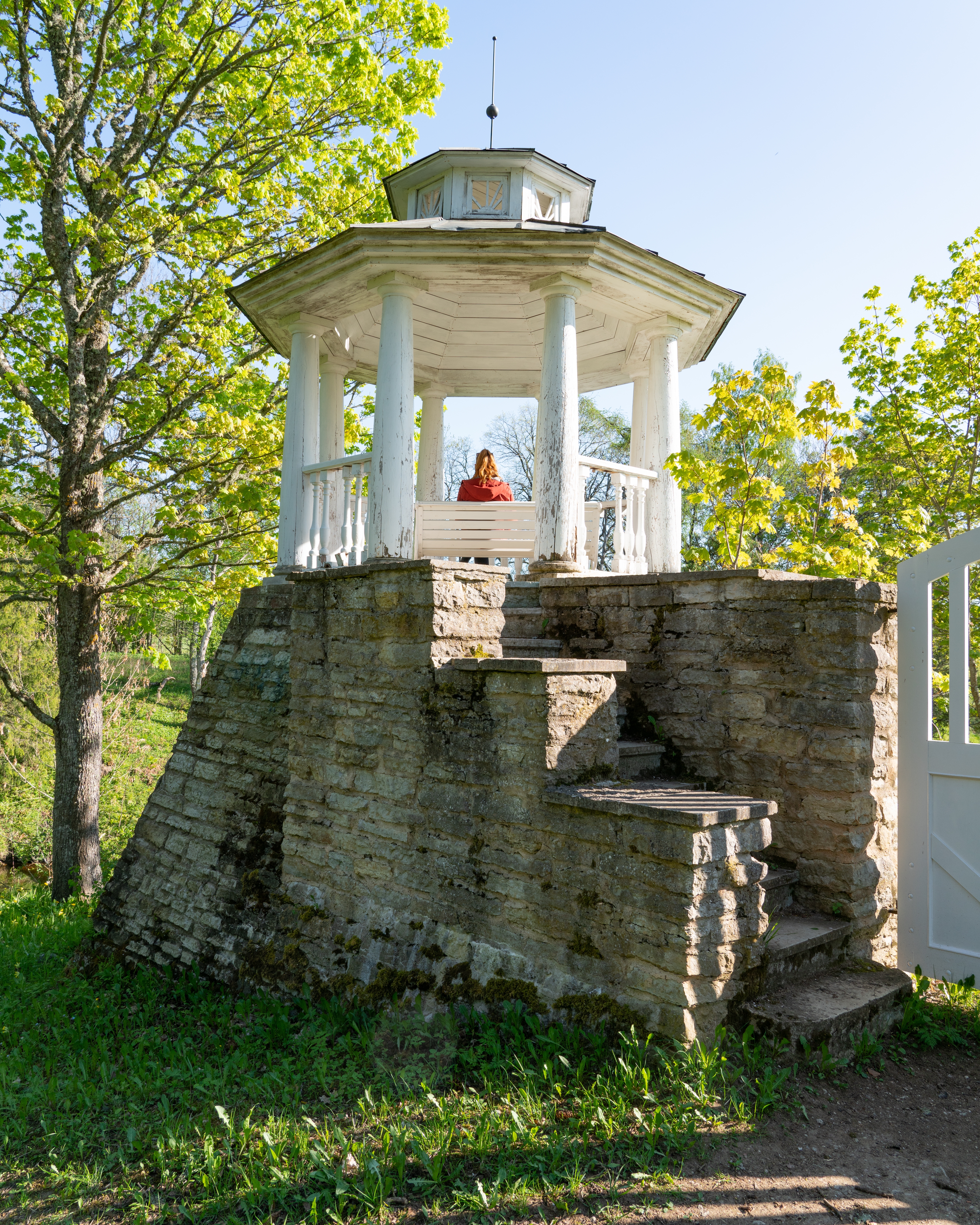 Kvinde nyder udsigten fra træpavillonen på den historiske danske herregård Vihula i Estland med udsigt over haven og floden