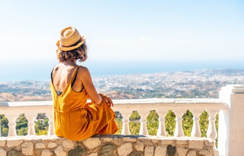 Ung kvinde nyder udsigten fra udsigtspunkt i Mijas med hvide huse og bjerge i Andalusien, Spanien