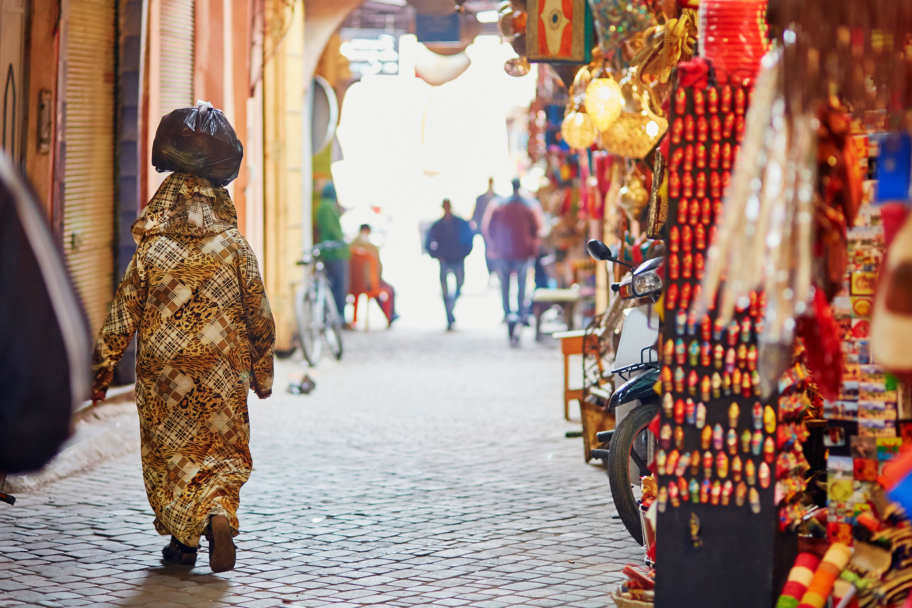 Kvinder handler på det traditionelle marokkanske souk-marked i Marrakech Medina med farverige varer og autentisk markedsstemning