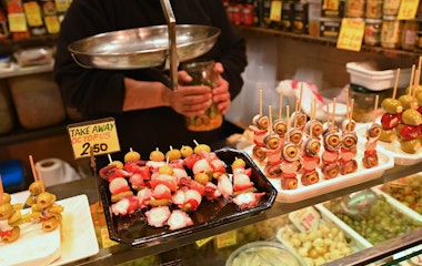 Farverige tapas og friske madvarer på La Boqueria marked i Barcelona med frugtspyd og traditionelle spanske delikatesser