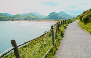 Smuk kyststi langs dramatiske klipper i Lagos med betagende havudsigt, træhegn og frodigt grønt landskab, perfekt til vandring i Algarve