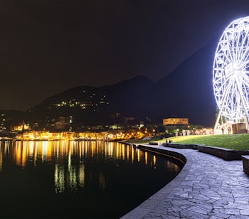 Oplyst pariserhjul i aftenmørket ved Laveno-Mombello med udsigt over Lago Maggiore og de smukke bjerge i Lombardiet, Italien