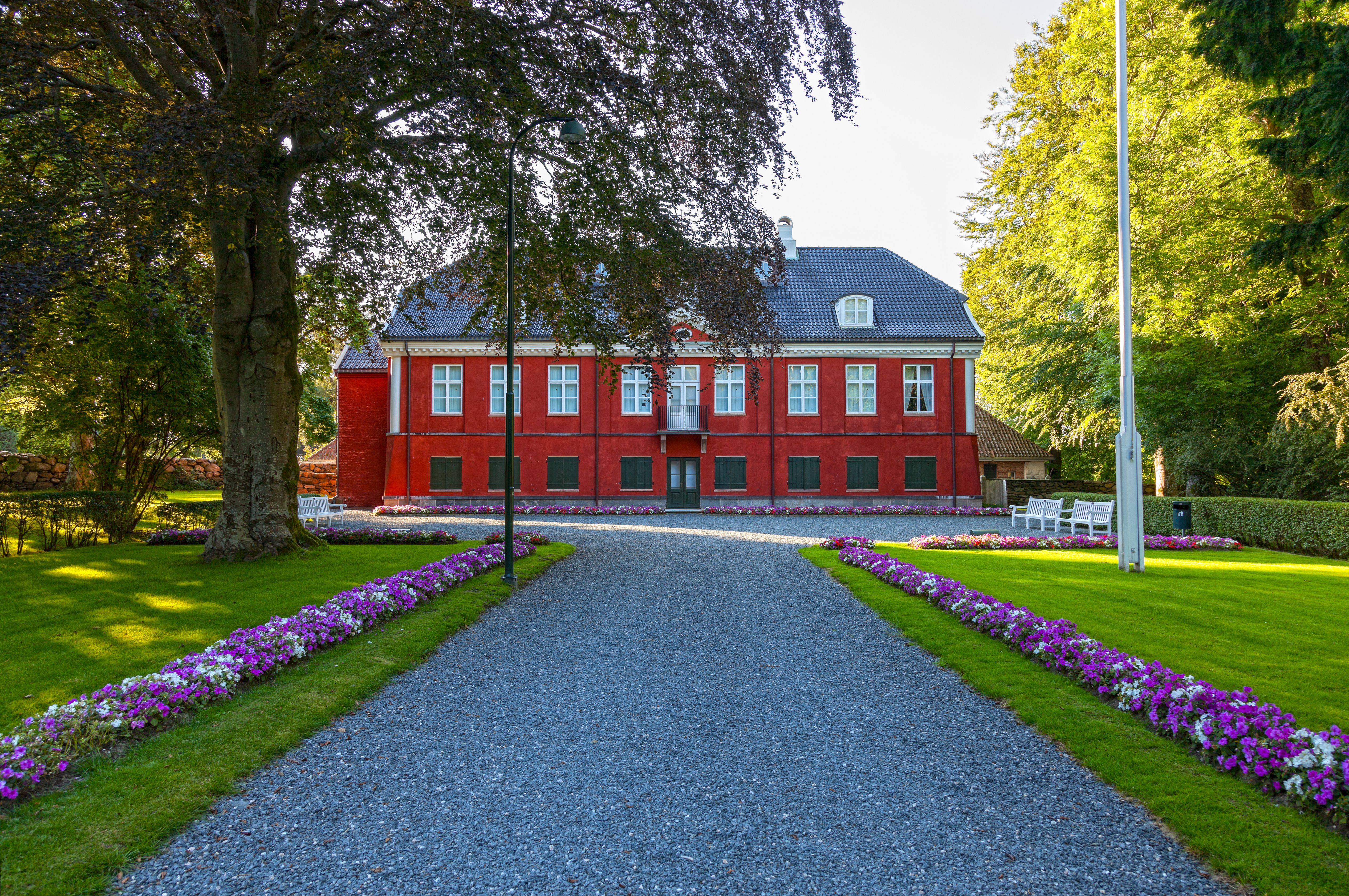 Historisk rødt Ledaal slot med smukke haver og lilla blomster i Stavanger Norge