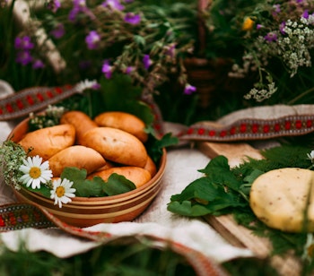 Traditionel lettisk Ligo midsommerfest med vilde blomster, hjemmelavet ost og øl på et rustikt træbord i den lettiske sommer
