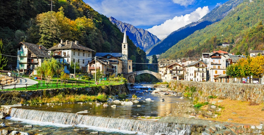 Idyllisk alpelandsby Lillianes med traditionelle stenhuse og en charmerende bro over floden, omgivet af majestætiske bjerge i Valle d'Aosta, Norditalien
