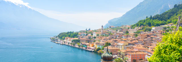 Panoramaudsigt over den smukke italienske by Limone sul Garda ved Gardasøen med terrakottafarvet hustage og alpine bjerge i baggrunden
