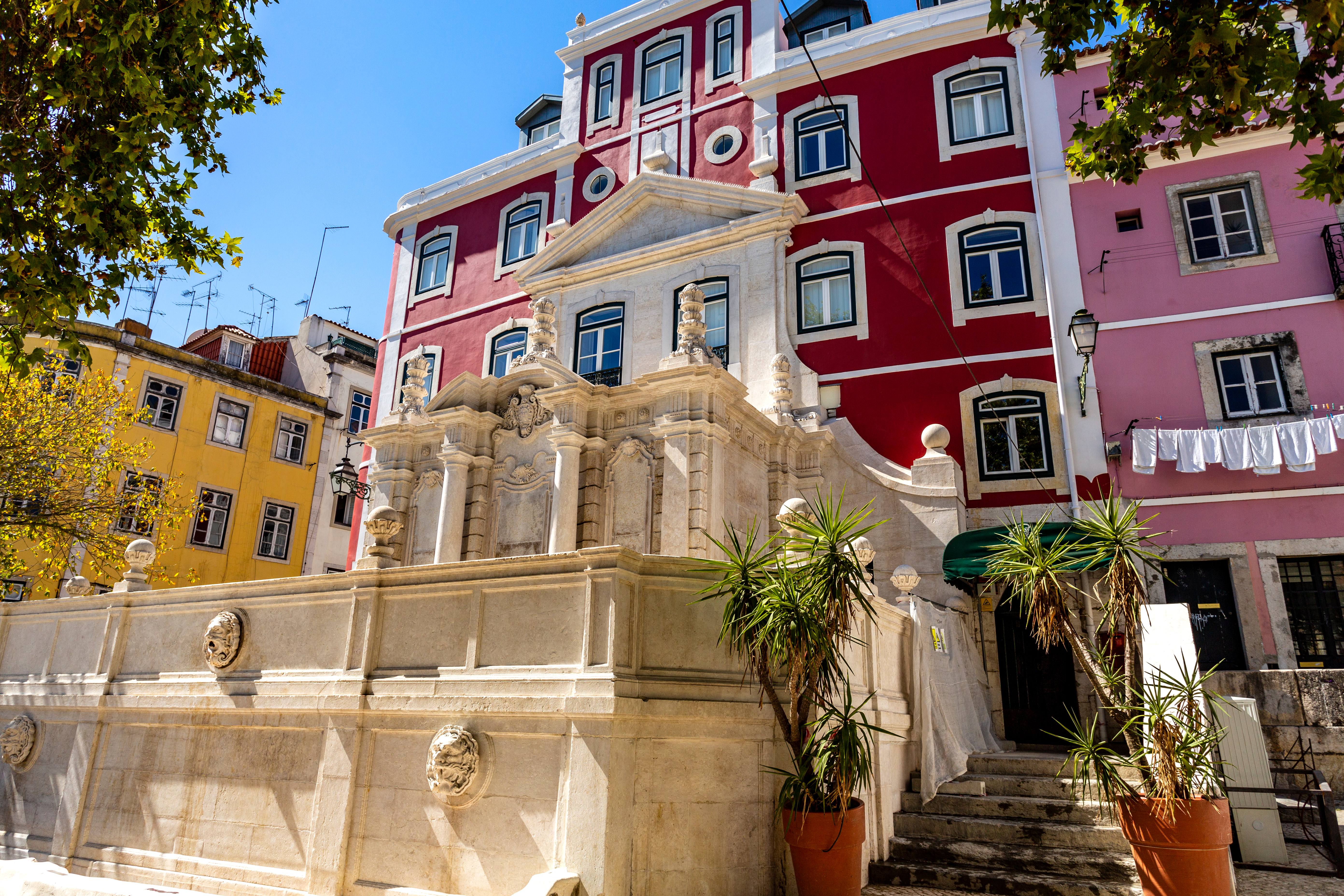 Smuk barok springvand med farverige historiske bygninger i Lissabon Portugal