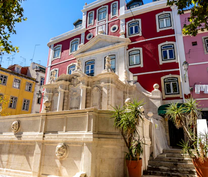Smuk barok springvand med farverige historiske bygninger i Lissabon Portugal