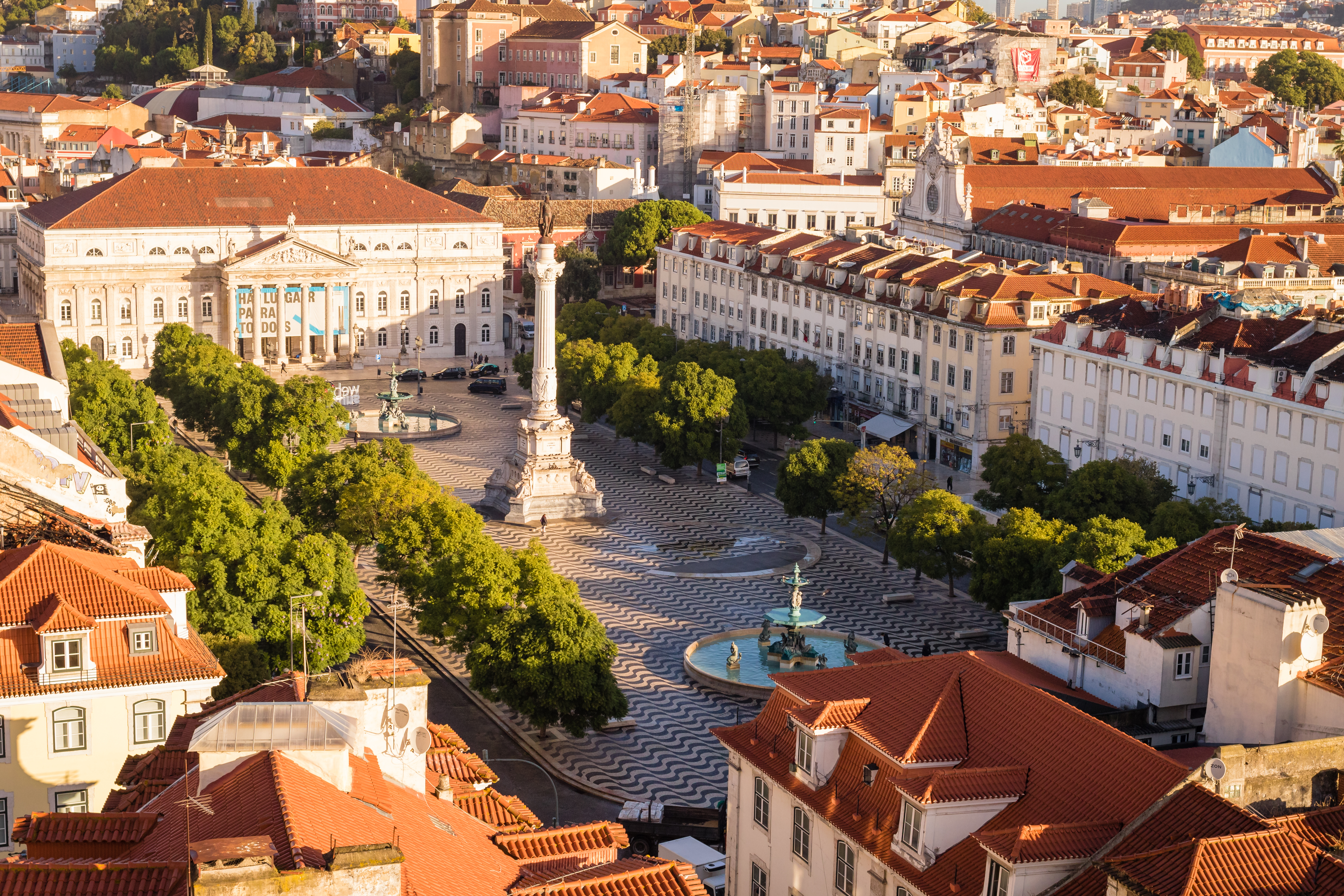 Panoramaudsigt over Lissabons historiske bykerne med traditionelle røde tegltagsstrækning og klassisk portugisisk arkitektur i gyldent morgenlys