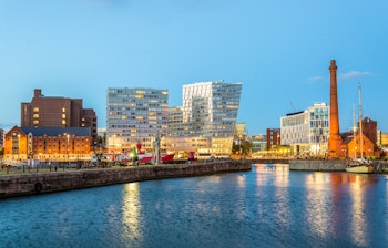 Den historiske Canning Dock i Liverpool oplyst om aftenen med smukke refleksioner i vandet og ikoniske bygninger ved havnefronten