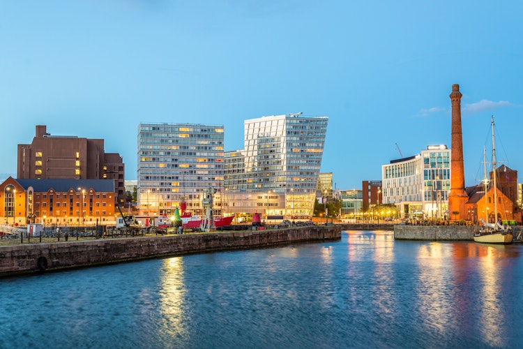 Den historiske Canning Dock i Liverpool oplyst om aftenen med smukke refleksioner i vandet og ikoniske bygninger ved havnefronten