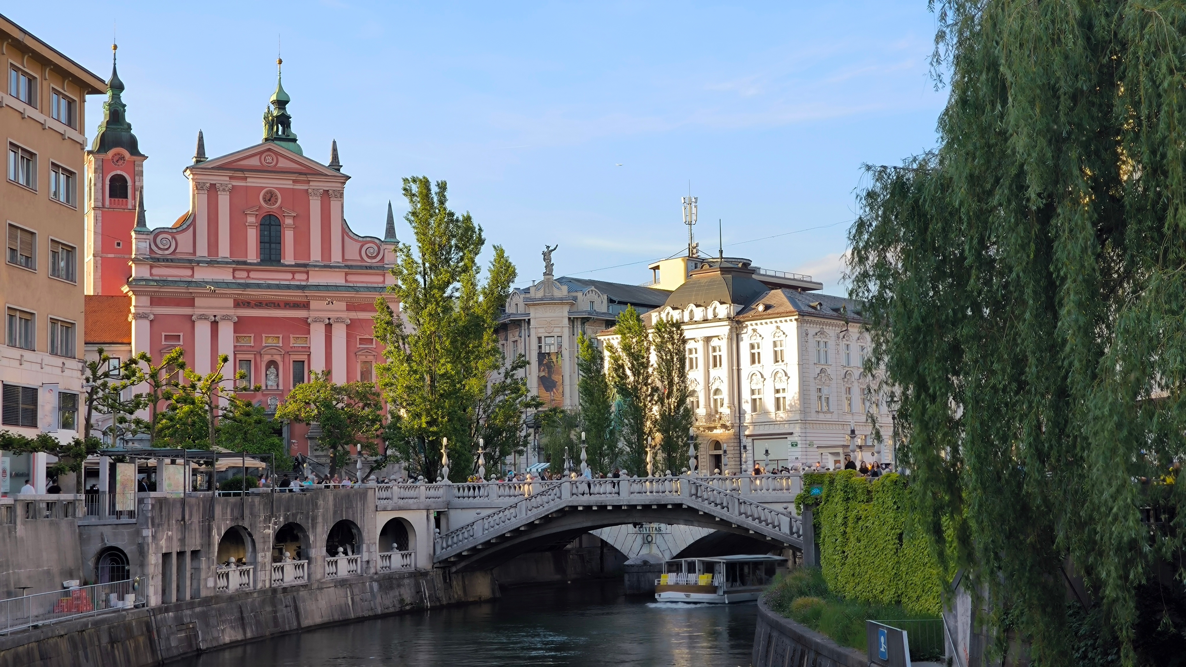 Smuk udsigt over Ljubljanica floden med den røde franciskanerkirke og Tromostovje bro i Ljubljana Slovenien
