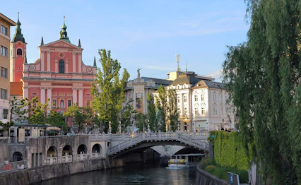 Smuk udsigt over Ljubljanica floden med den røde franciskanerkirke og Tromostovje bro i Ljubljana Slovenien