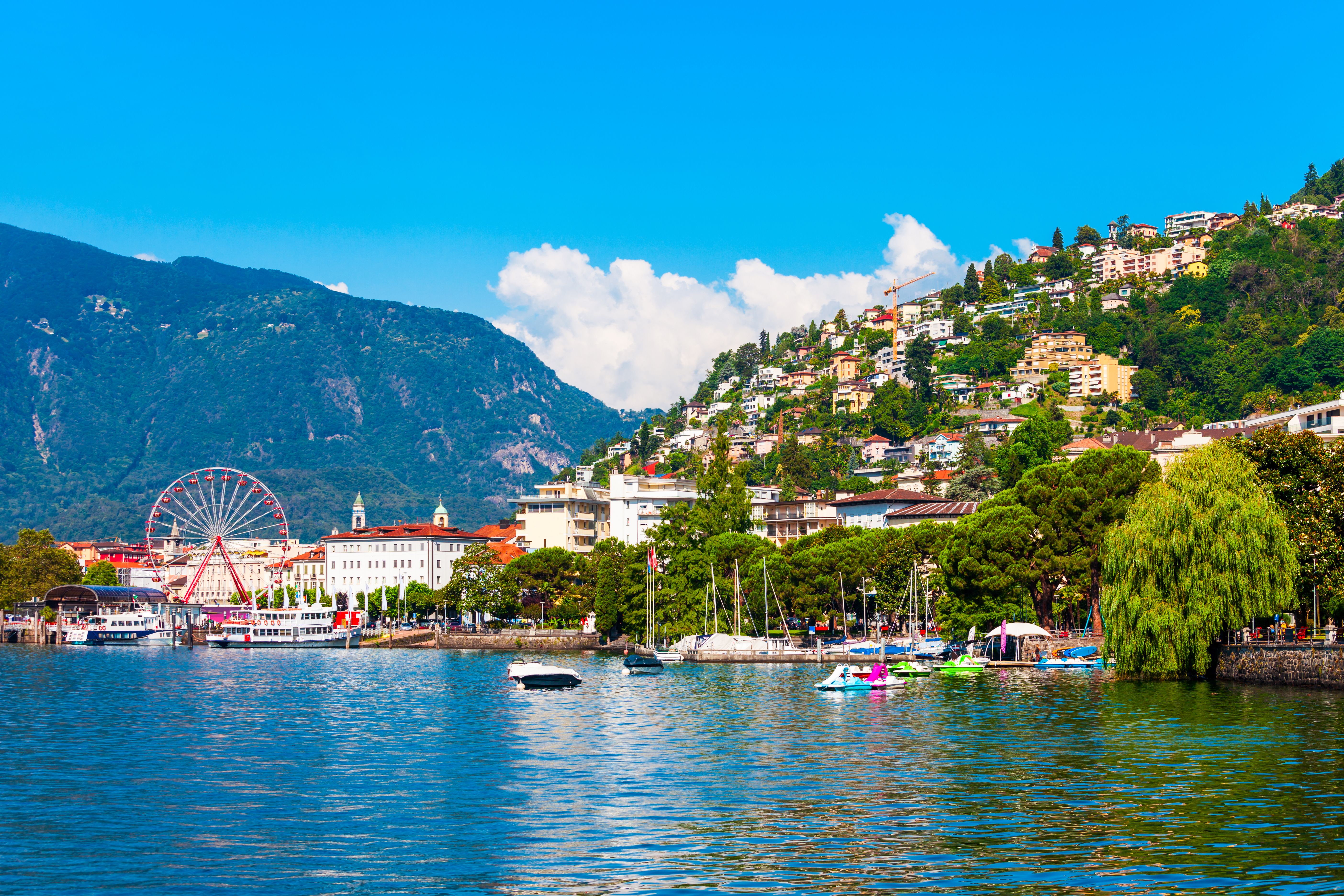 Panoramaudsigt over Locarno by ved Lago Maggiore i Ticino, Schweiz med farverige bygninger og alper i baggrunden