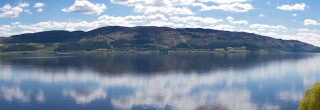 Panoramaudsigt over Loch Ness med perfekte skyrefleksioner på det rolige vand i de skotske højlande
