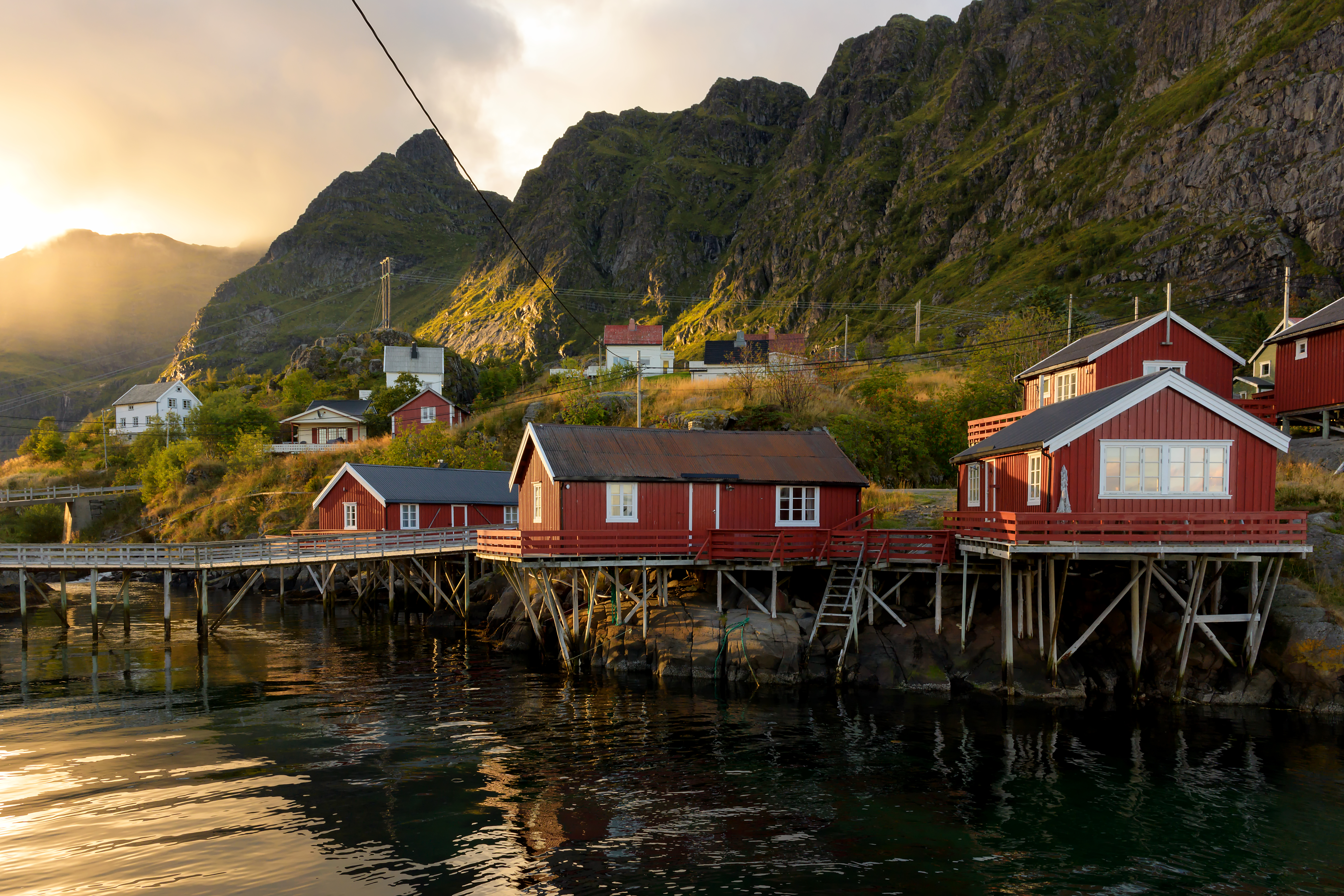 Traditionelle røde fiskehuse på stylter i Lofoten, Norge ved solnedgang
