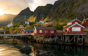Traditionelle røde fiskehuse på stylter i Lofoten, Norge ved solnedgang