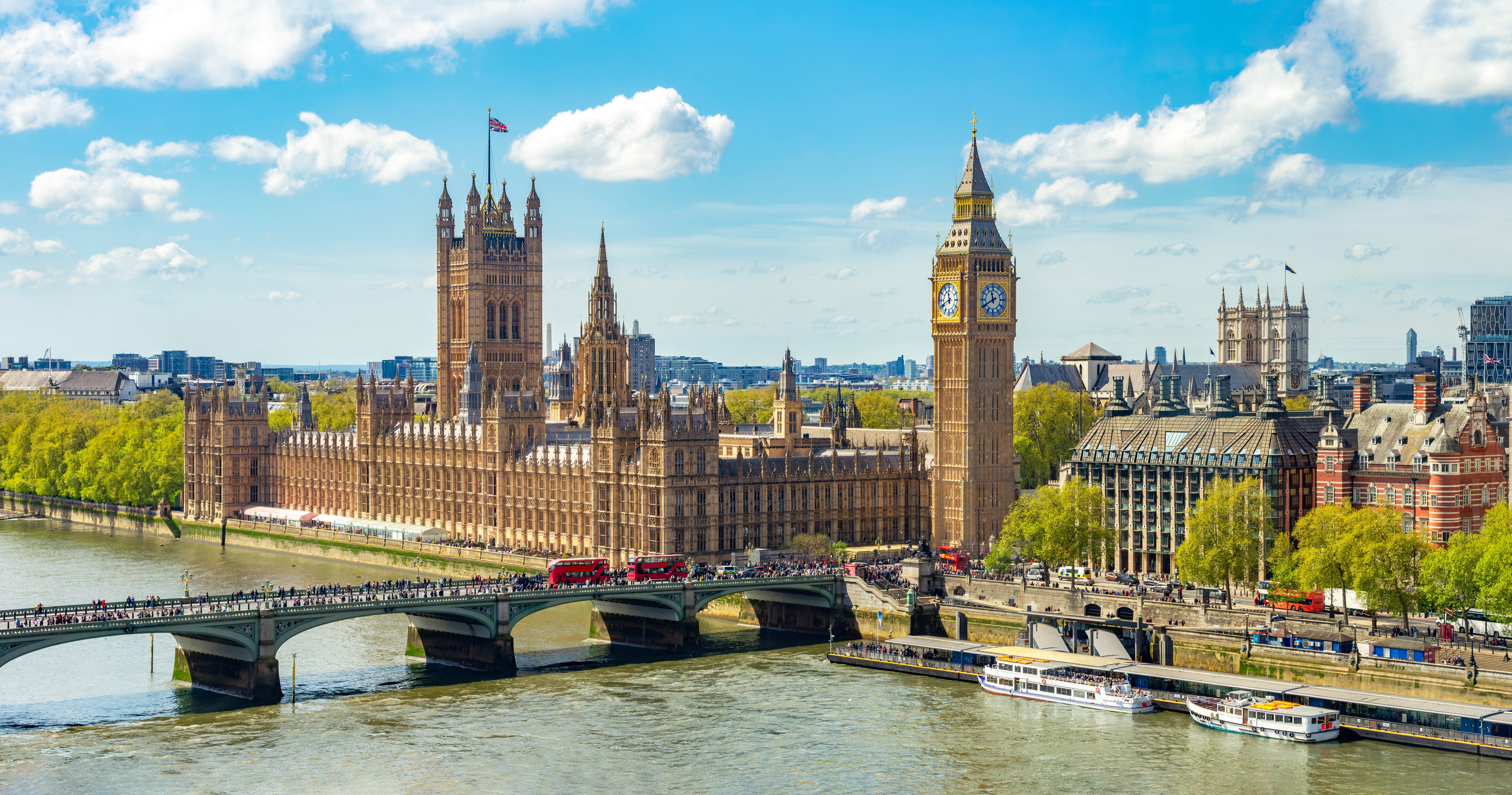 Imponerende udsigt over Londons berømte skyline med Houses of Parliament og Big Ben-tårnet langs Themsen-floden - et ikonisk symbol på Storbritanniens historiske hovedstad