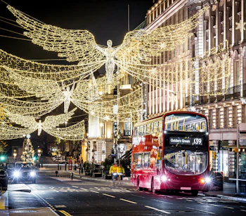Regent Street i London pyntet med strålende julelys formet som engle og en rød dobbeltdækker bus om natten