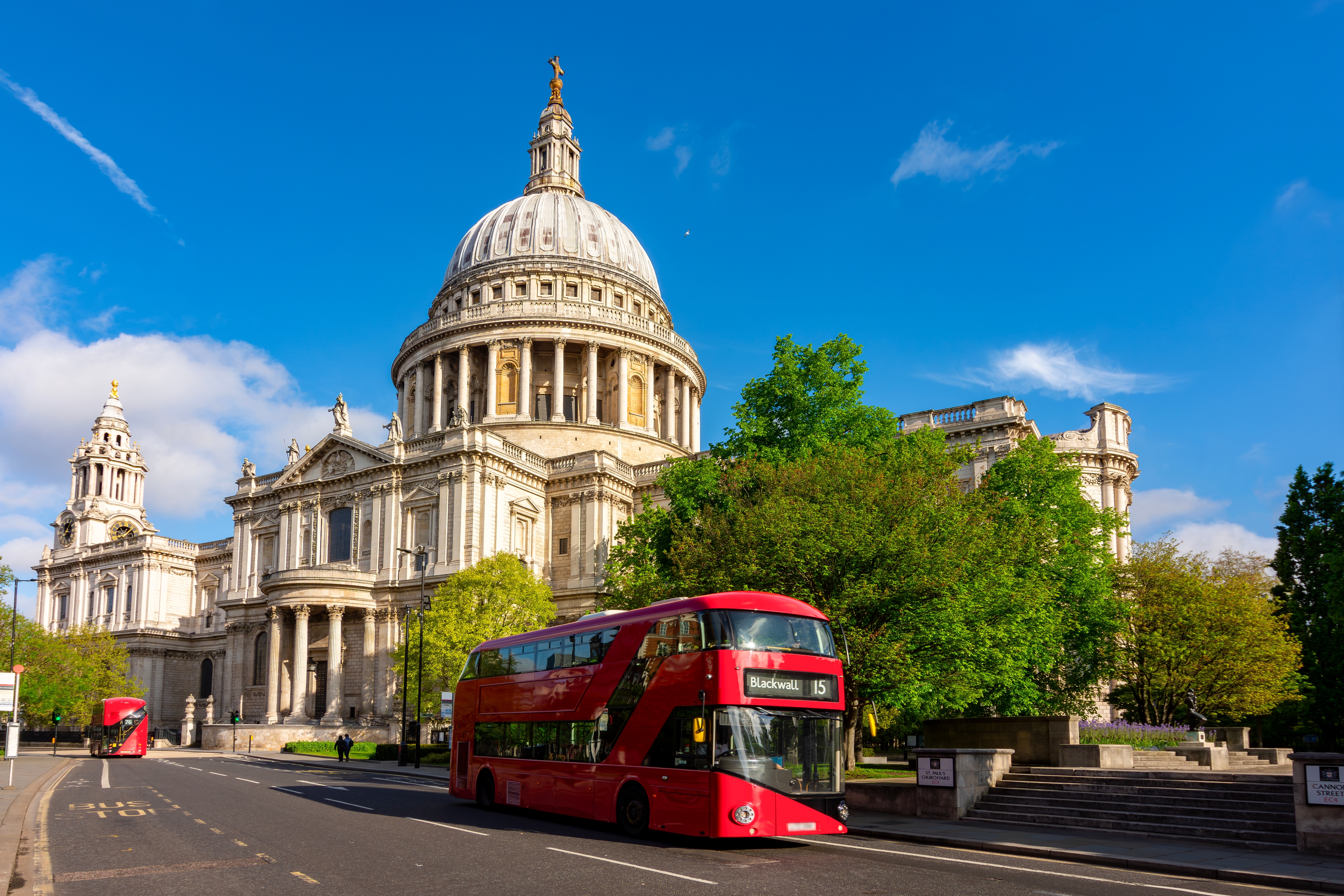 Ikonisk udsigt over London med St. Paul's Cathedral og en rød dobbeltdækkerbus, perfekt til storbyferien i den britiske hovedstad