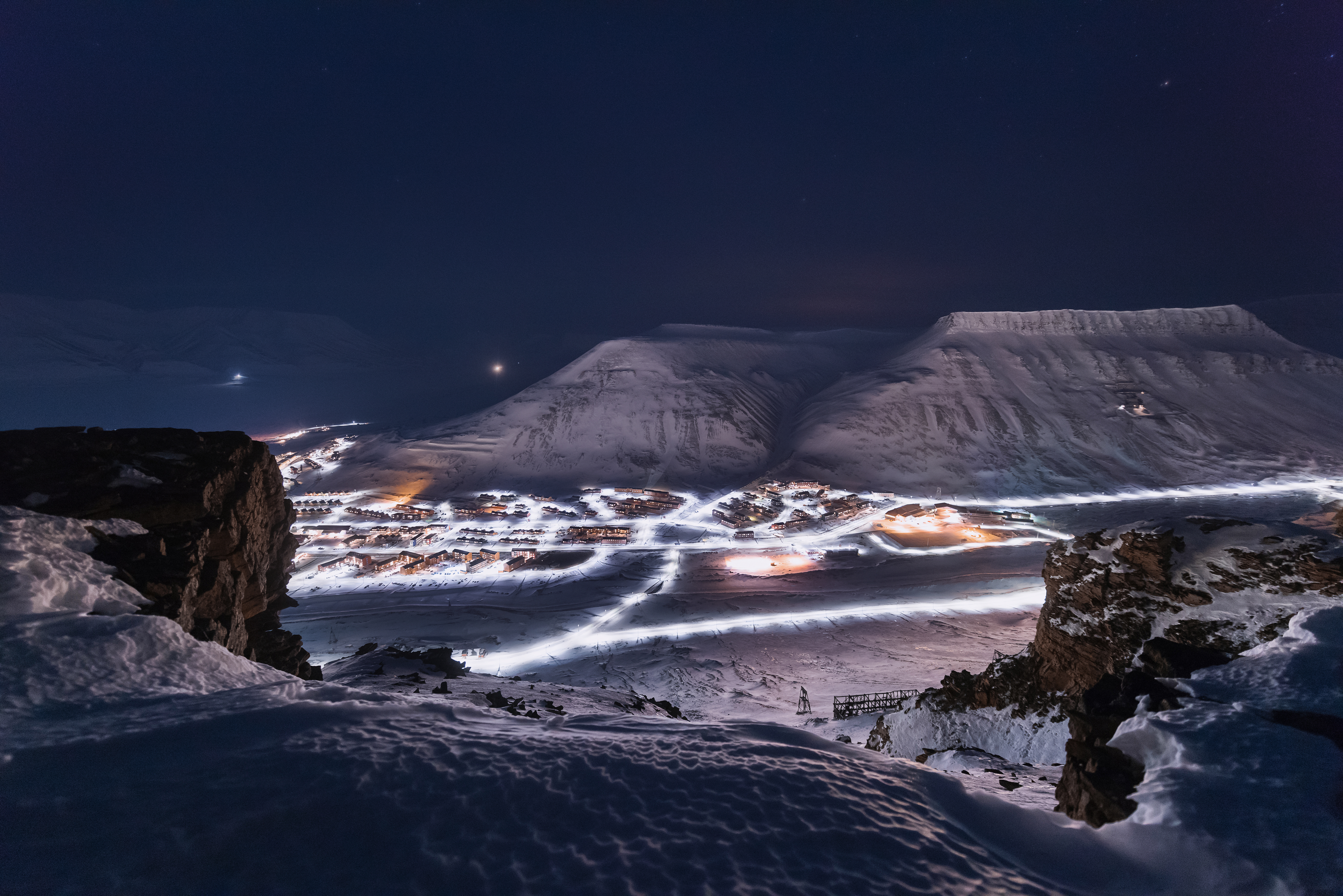 Longyearbyen by om natten med snedækte bjerge under arktisk himmel på Svalbard i Norge
