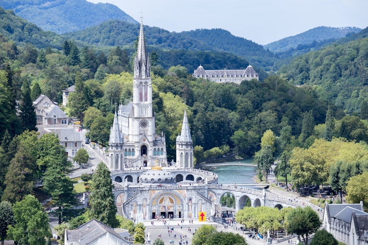 Helligdommen i Lourdes med den hvide basilika omgivet af Pyrenæerne, et berømt pilgrimsmål i Sydfrankrig