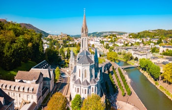 Luftfoto af Vor Frue af Lourdes Helligdommen, et berømt katolsk pilgrimsmål i Pyrenæerne i Sydfrankrig med den ikoniske basilika og religiøse bygninger
