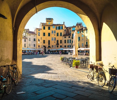 Charmerende middelalderlig gade i Luccas historiske centrum med traditionel italiensk arkitektur, stenbygninger og buede døråbninger