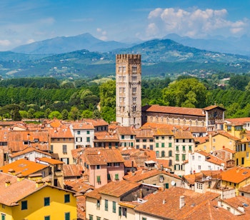 Panoramaudsigt over den historiske by Lucca i Toscana med karakteristiske terracotta-tage og smalle gader under en klar blå sommerhimmel