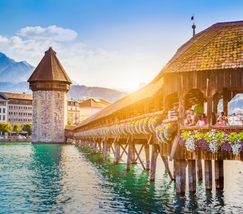 Magisk solnedgangsudsigt over Lucernes historiske centrum med den ikoniske træbro Kapellbrücke over floden Reuss og det majestætiske Mount Pilatus i baggrunden