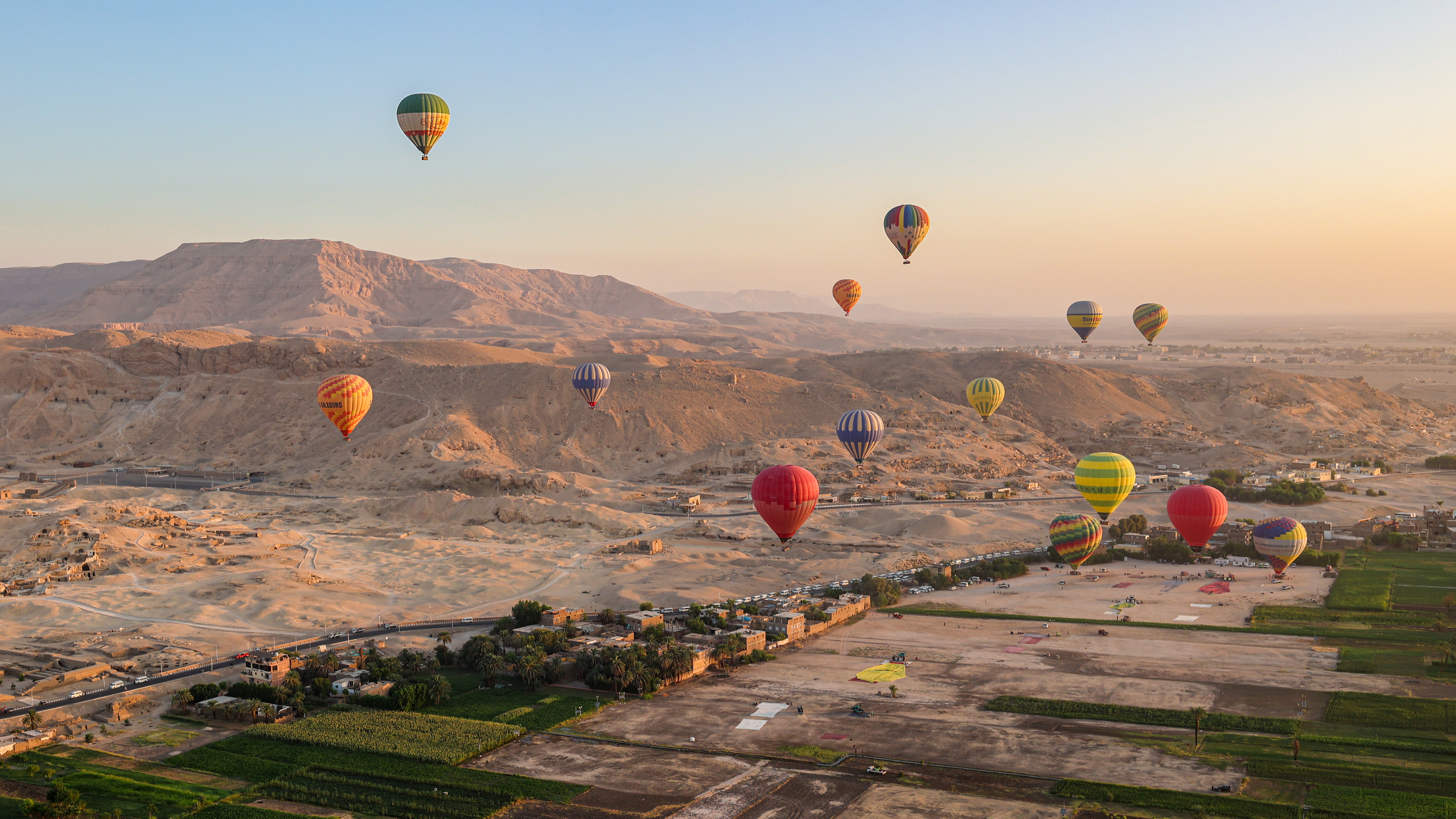 Farverige luftballoner svæver over Valley of the Kings ved solopgang i Luxor, Egypten, med ørkenbjerge i baggrunden
