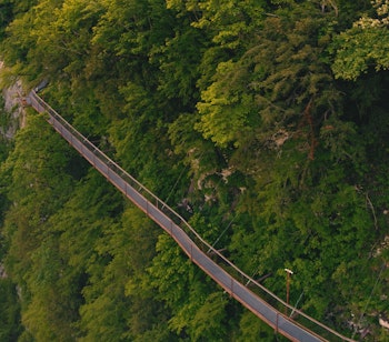 Luftfoto af smuk bjergbro omgivet af frodig grøn skov og dramatiske klipper